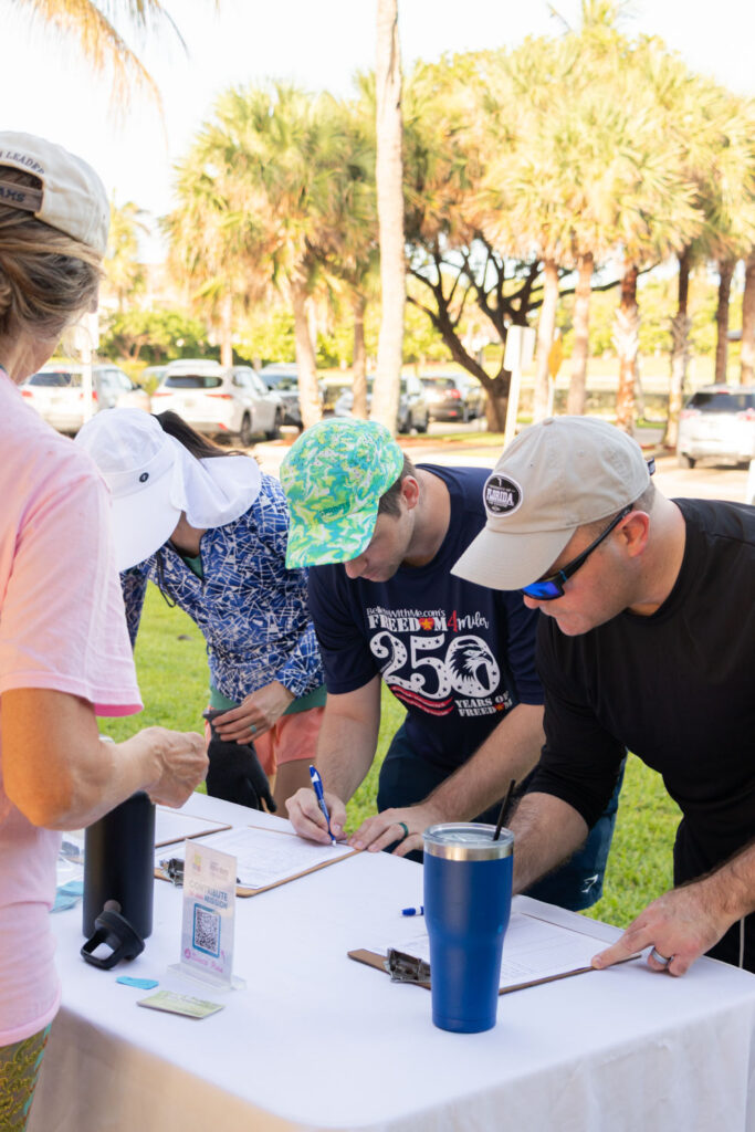 Two volunteers checking in at the registration table before the beach cleanup.