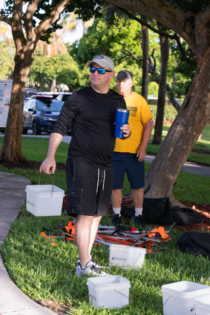 Volunteer carrying a bucket of cleanup supplies along a park pathway.