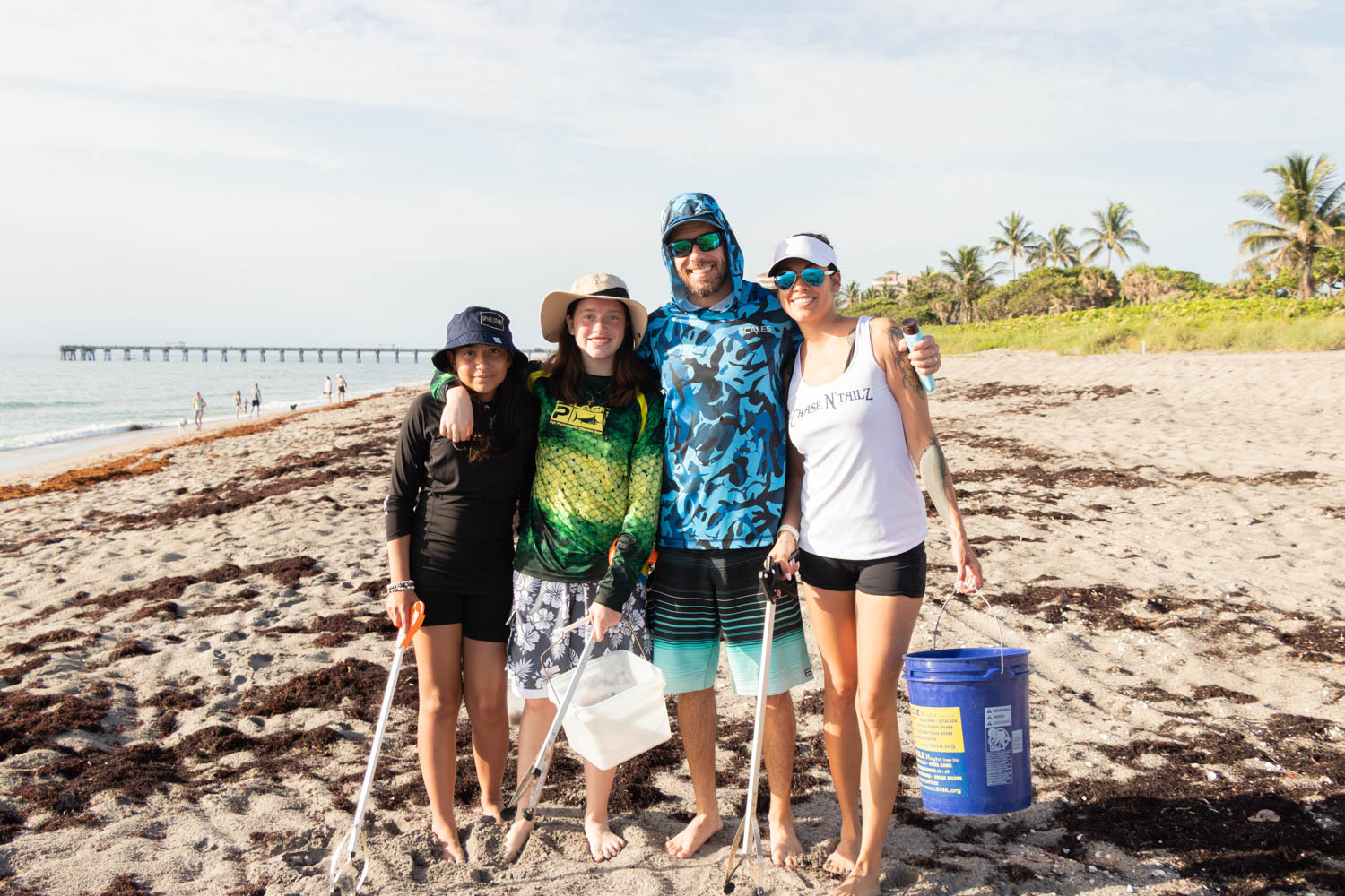 Group of volunteers posing together on the beach with cleanup buckets.