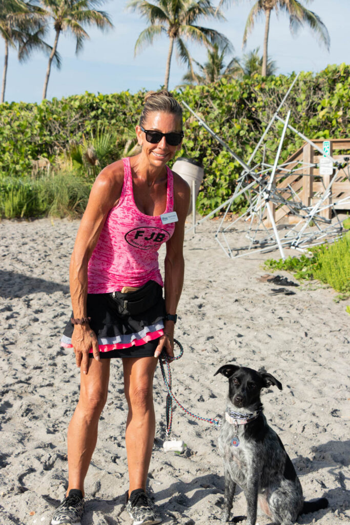Volunteer with a black dog standing on the beach during the cleanup.
