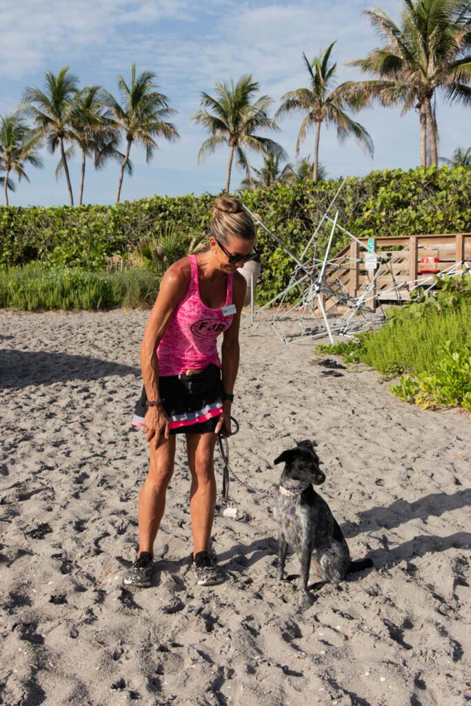 Volunteer with a black dog standing on the beach during the cleanup.
