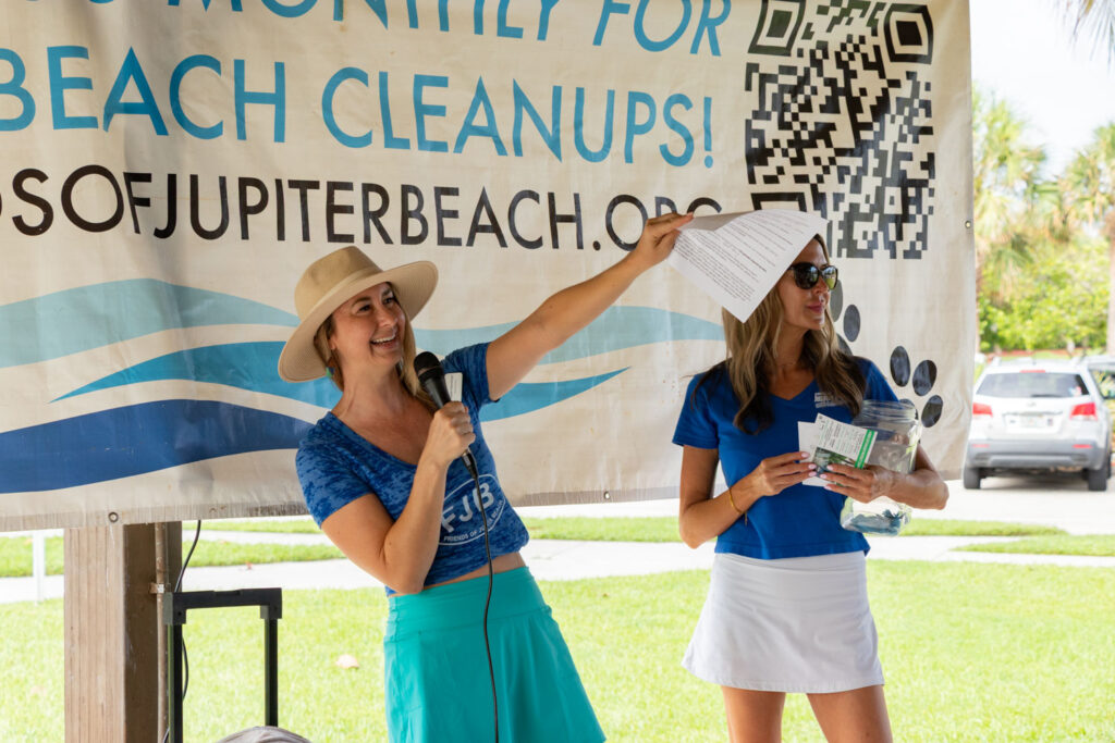 Event volunteer speaking near the Friends of Jupiter Beach cleanup banner.