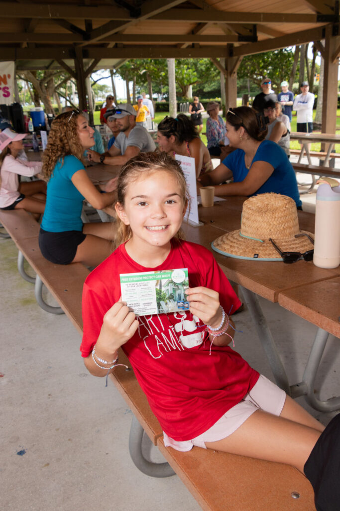 Child smiling while seated at a picnic table during the event.
