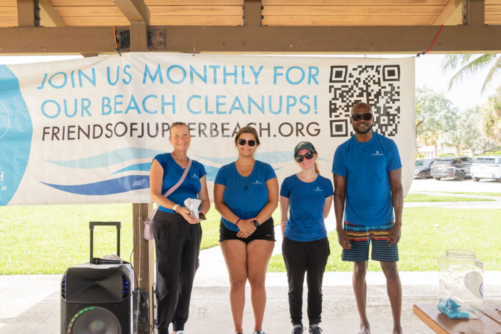 Group of volunteers smiling together beneath the Friends of Jupiter Beach cleanup banner.