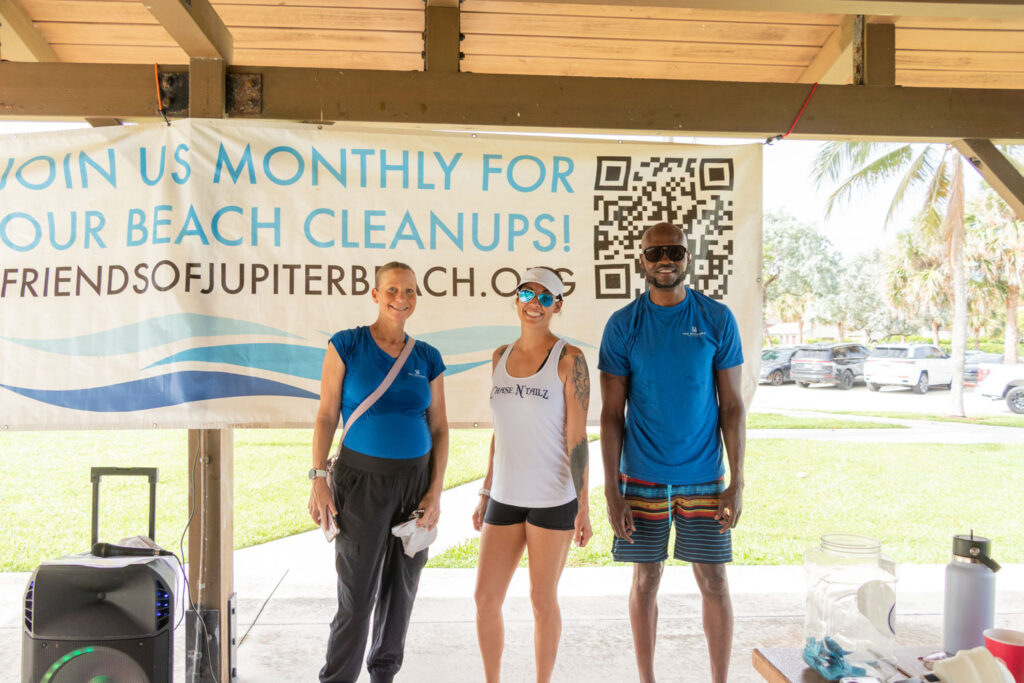 Group of volunteers smiling together beneath the Friends of Jupiter Beach cleanup banner.
