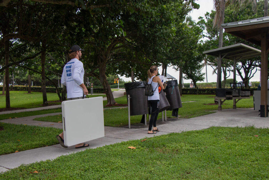 Friends of Jupiter Beach volunteers carrying supplies along beach path.