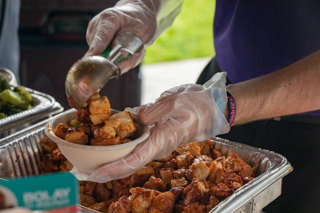 Bolay food being portioned into paper bowl.
