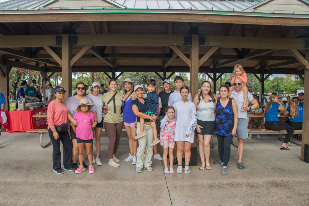 Group of volunteers posed and smiling under Anita Lankler Pavilion in Juno Beach.