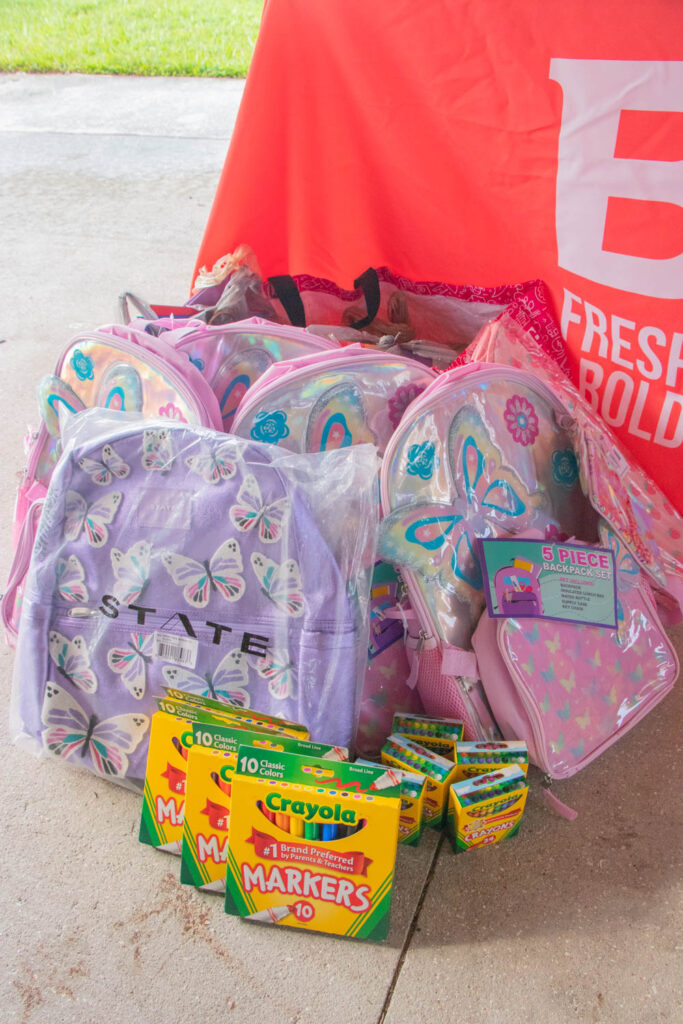 Assortment of donated school supplies including notebooks, backpacks, and colored pencils.
