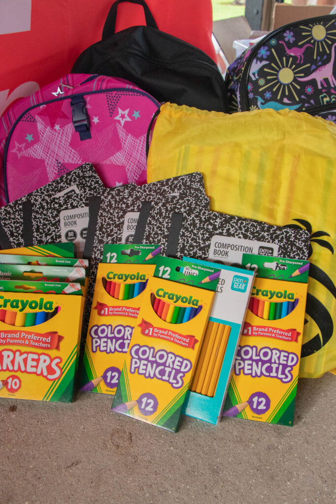 Assortment of donated school supplies including notebooks, backpacks, and colored pencils.