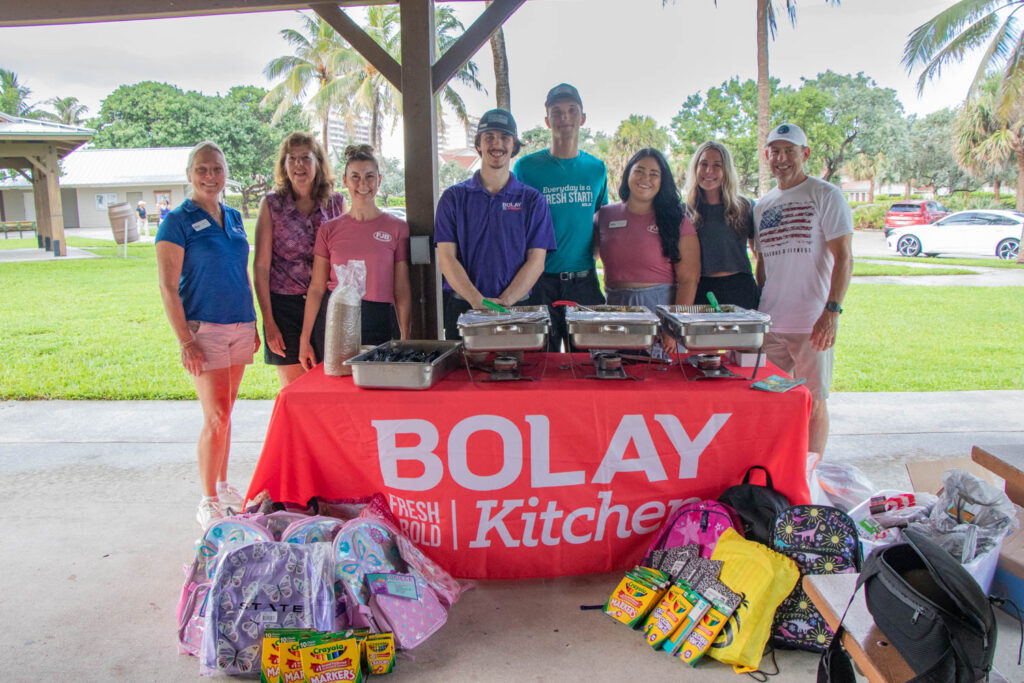 Volunteers standing in front of Bolay table with donated school supplies.