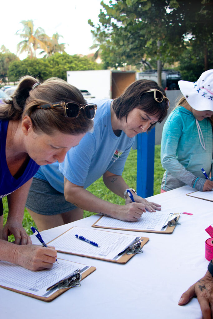 International Coastal Cleanup volunteers signing in on clip boards.