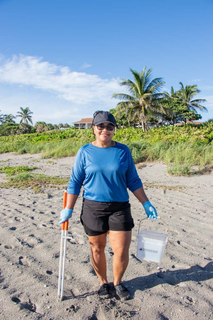 International Coastal Cleanup volunteer with a trash bucket and picker on Jupiter Beach.