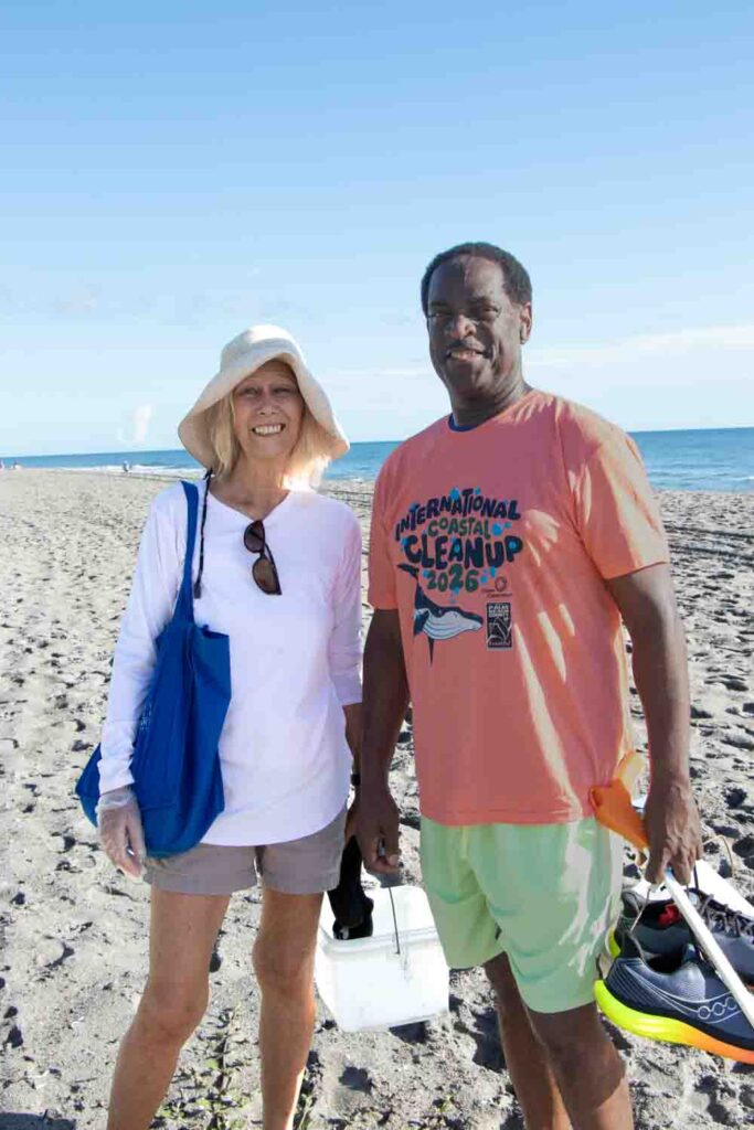 International Coastal Cleanup volunteers on the beach holding trash buckets.