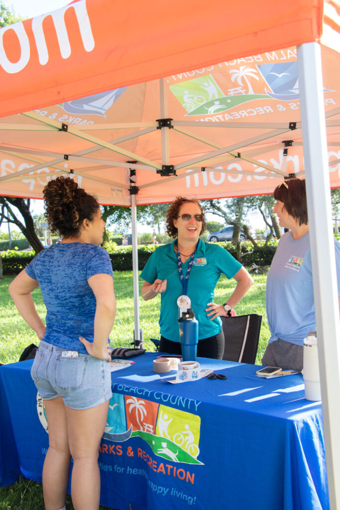 Parks and Recreation volunteers chatting under their tent at Friends of Jupiter Beach cleanup.