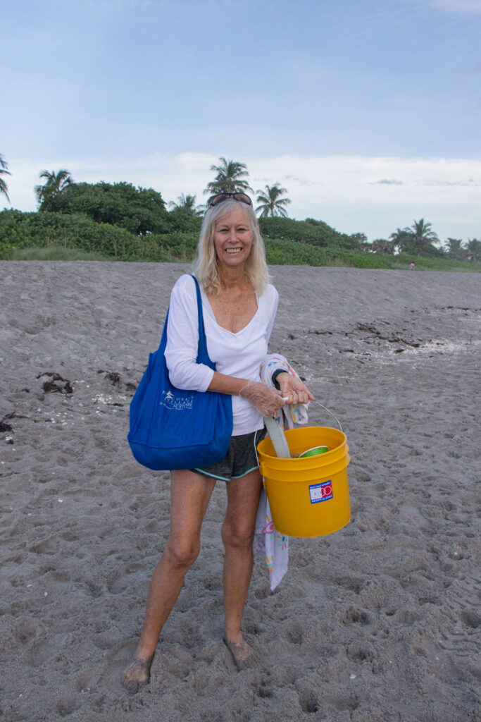 Cleanup volunteer holding cleanup bucket on the beach.