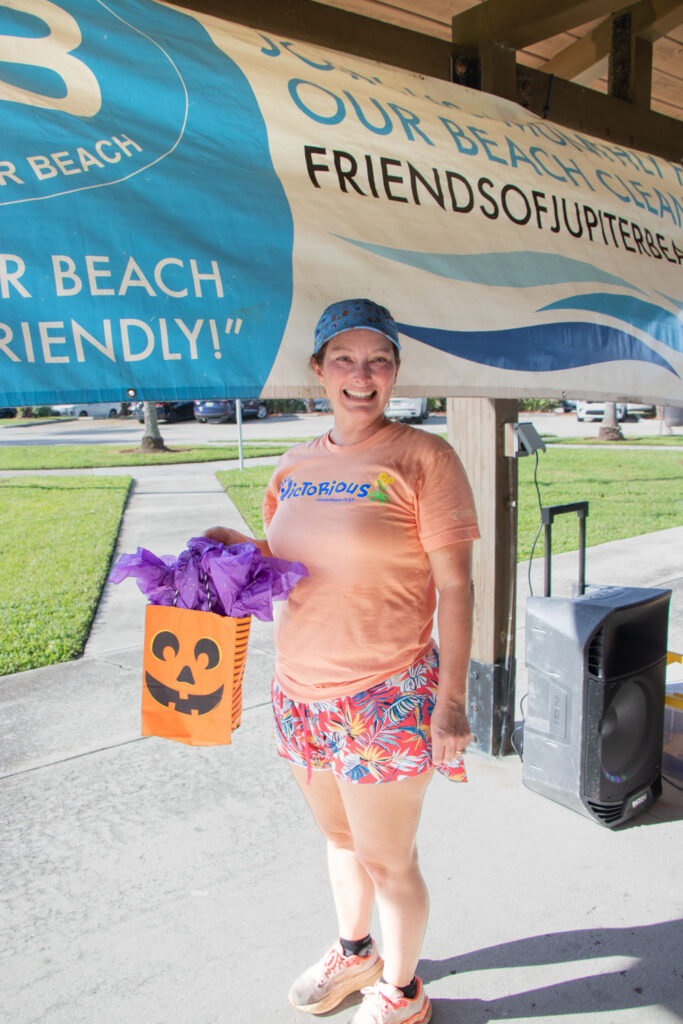 Friends of Jupiter Beach raffle winner smiling with a pumpkin gift bag.